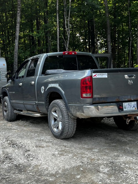 Trucky Le Deux, a gray pickup truck parked on a gravel road near the woods.